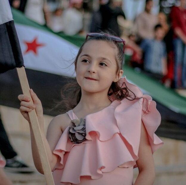 Syrian girl holding Syrian flag.