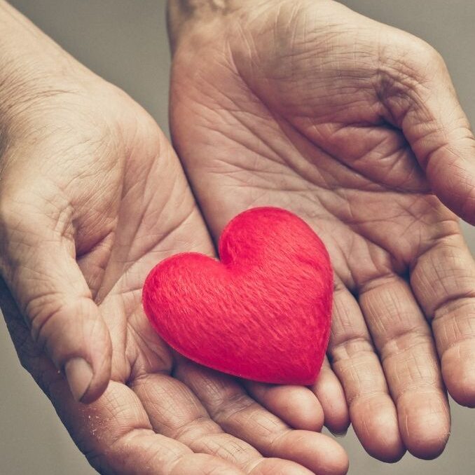 Hands giving a heart to represent charitable giving