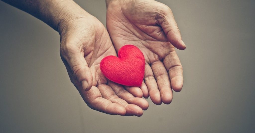 Hands giving a heart to represent charitable giving