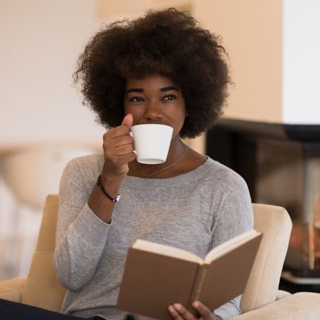 A woman relaxing with a book and tea.